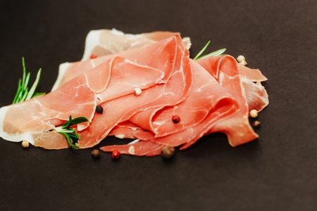 Pieces of dried pork jamon prosciutto on a black board.の写真素材