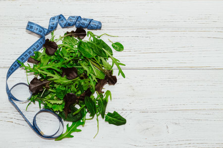 A mixture of lettuce leaves different types with a centimeter for weight loss on a table.の写真素材
