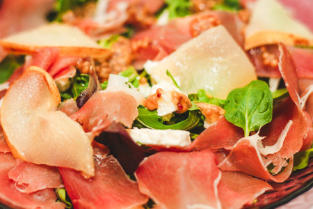 Salad with herbs, arugula, prosciutto, cheese, green olives and nuts.の写真素材