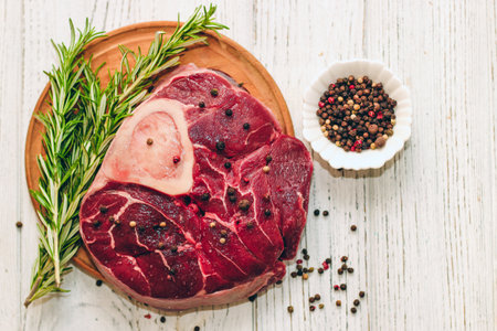 Fresh piece of meat large beef steak on the bone ossobuco with pepper, rosemary on the board.の写真素材