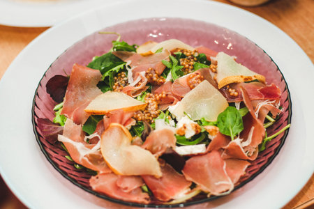 Salad with herbs, arugula, prosciutto, cheese, green olives and nuts.の写真素材