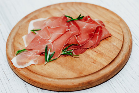 Pieces of dried pork jamon prosciutto on a wooden board.の写真素材