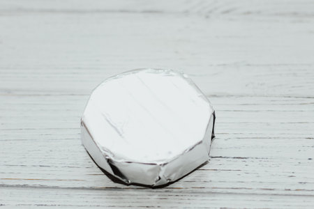 Camembert cheese wrapped in a package with foil on the table.の写真素材