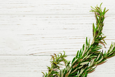 Sprigs of rosemary spices on a table with wooden boards, space for text.の写真素材