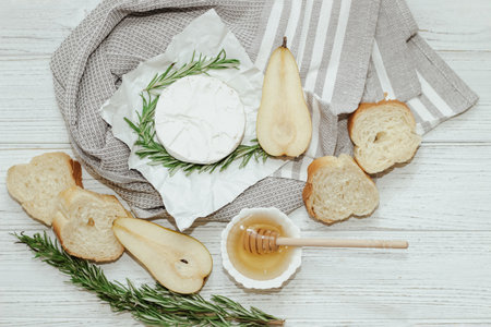 Camembert cheese with pear and rosemary sprig with honey on the table.の写真素材