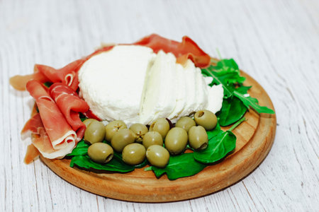 Pieces of dried pork jamon prosciutto with olives and cheese on the board.の写真素材