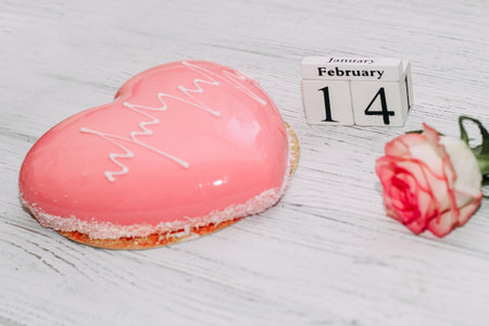 Pink tea rose with heart shaped pink mousse cake and February 14 calendar.の写真素材