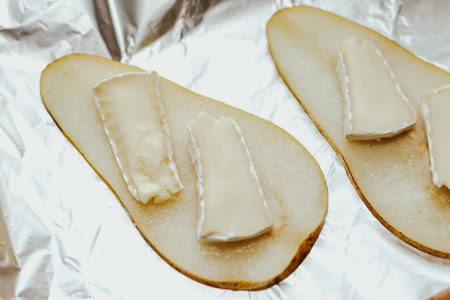 Pieces of ripe pear with Camembert cheese on the table.の写真素材