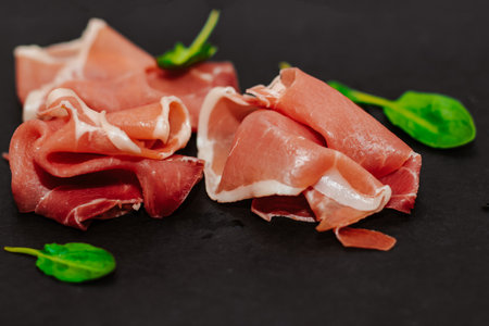Pieces of dried pork jamon prosciutto on a black board.の写真素材