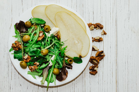 Salad with pears, herbs, arugula, prosciutto, cheese, green olives and nuts.の写真素材