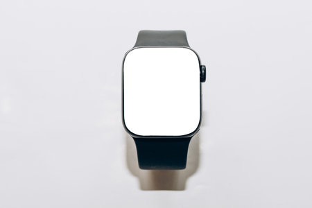 A black technological smart watch lies on a wooden background with a white screen for text spaceの写真素材