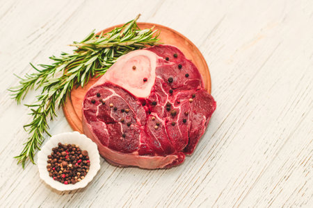 Fresh piece of meat large beef steak on the bone ossobuco with pepper, rosemary on the board.の写真素材