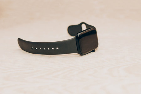 A black technological smart watch lies on a wooden background.の写真素材