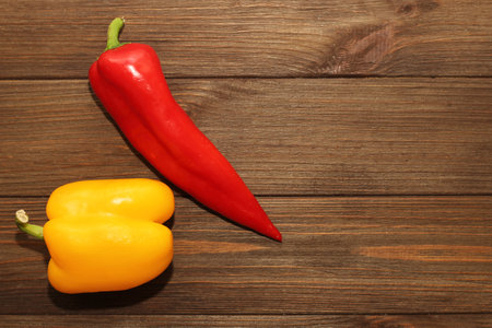 Red pepper Kapi with yellow sweet pepper on a wooden background, space for text.の写真素材