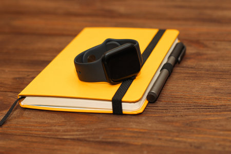 A black technological smart watch lies on a notepad for time management.の写真素材