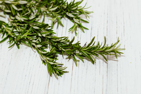 Sprigs of rosemary spices on a table with wooden boards, space for text.の写真素材