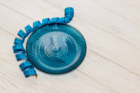 empty blue plate with centimeter on background, diet proper nutrition concept.の写真素材