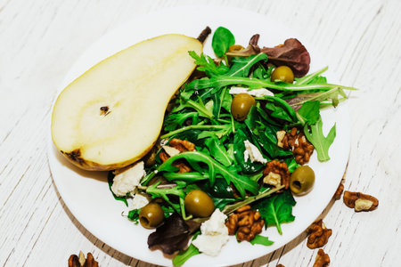 Salad with pears, herbs, arugula, prosciutto, cheese, green olives and nuts.の写真素材