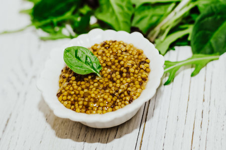 grain mustard with a green leaf, salad dressing in a white bowl.の写真素材