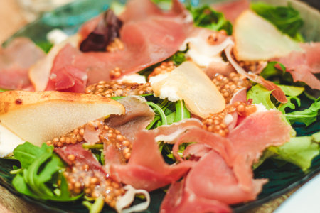 Salad with herbs, arugula, prosciutto, cheese, green olives and nuts.の写真素材