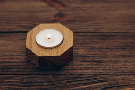 Wax and aromatic candle in a wooden candlestick stands on a wooden table.の写真素材