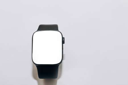 A black technological smart watch lies on a wooden background with a white screen for text spaceの写真素材