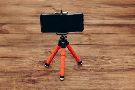 The phone stands on a manual monopod tripod for the camera on a wooden table..の写真素材