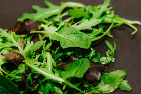 Mix of lettuce leaves different types on black table.の写真素材