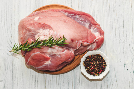 Fresh piece of meat large pork ham on a board with pepper and rosemary.の写真素材