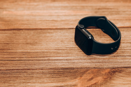 A black technological smart watch lies on a wooden background.の写真素材