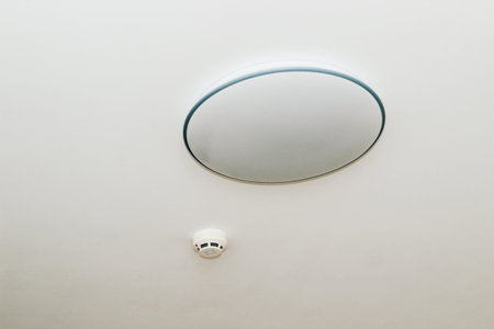 A fire alarm sensor on the ceiling with a chandelier.の写真素材