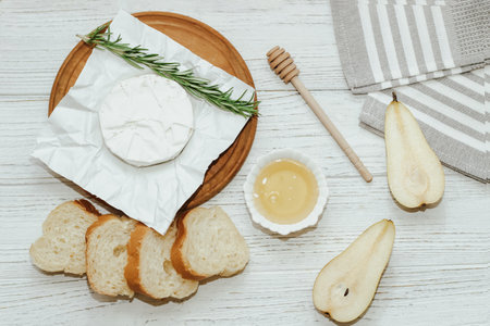 Camembert cheese with baguette croutons and a sprig of rosemary with honey on the table.の写真素材