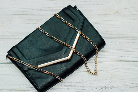 Black clutch bag with gold elements and a gold chain.の写真素材
