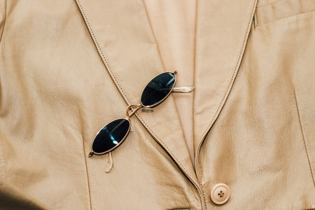 Gold-rimmed sunglasses on the texture of a brown leather jacket, genuine soft leather.の写真素材