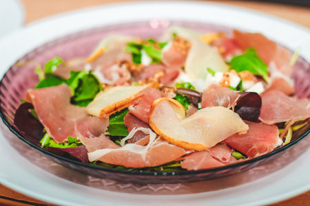 Salad with herbs, arugula, prosciutto, cheese, green olives and nuts.の写真素材