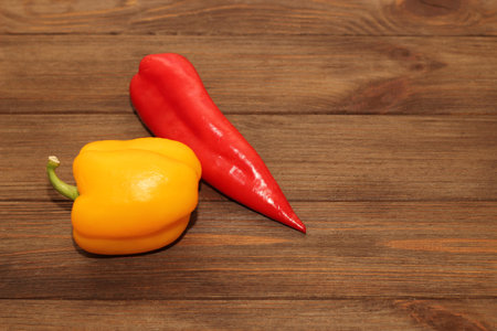 Red pepper Kapi with yellow sweet pepper on a wooden background, space for text.の写真素材