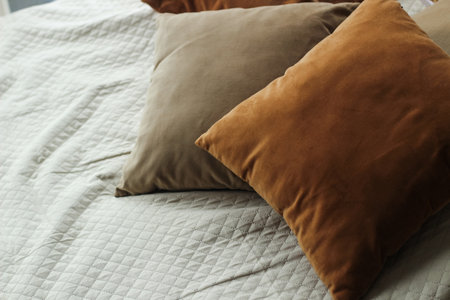 Decorative brown pillows on a sofa with a blanket.の写真素材