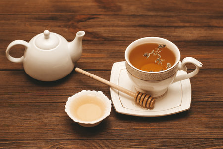 Liquid fresh linden honey in a plate with a wooden honey spoon and tea.の写真素材