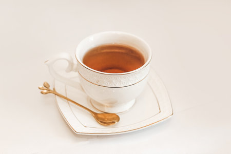 White cup with saucer and golden spoon and tea leaves.の写真素材