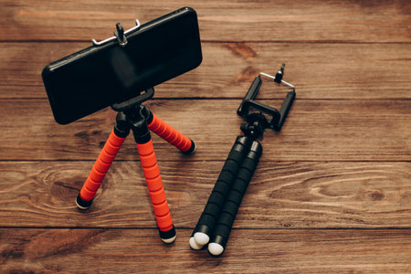 The phone stands on a manual monopod tripod for the camera on a wooden table..の写真素材