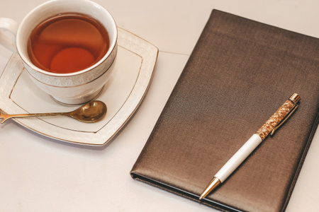 White cup and saucer with golden spoon and notepad.の写真素材