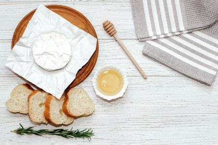 Camembert cheese with baguette croutons and a sprig of rosemary with honey on the table.の写真素材