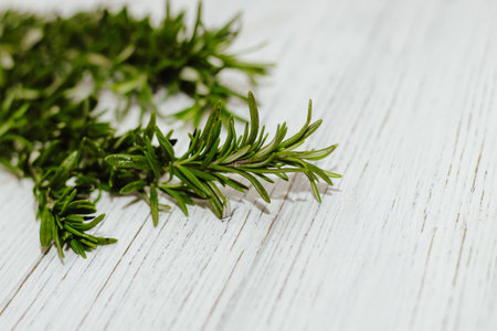Sprigs of rosemary spices on a table with wooden boards, space for text.の写真素材
