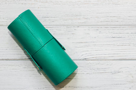 Green case with make-up bones on a wooden table.の写真素材