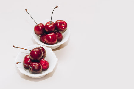 Ripe red cherries in white plates on the table.の写真素材