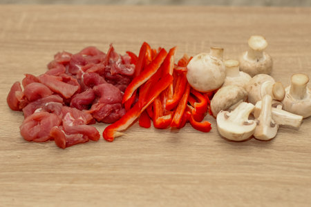 Sliced meat, champignons and red pepper on a board.の写真素材