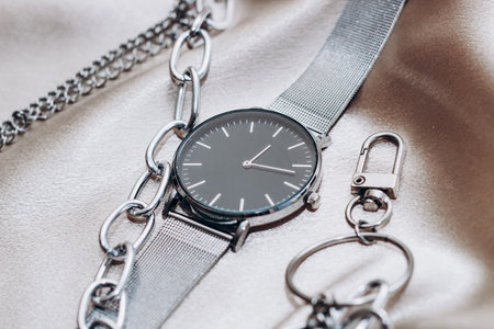 Stylish silver chain decorations for the neck and watch on a silk shiny background.の写真素材