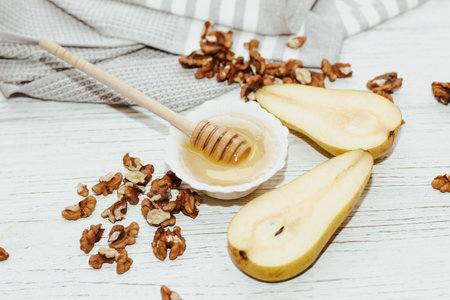 Liquid organic honey in white bowl with pears, wooden honey spoon.の写真素材