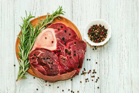 Fresh piece of meat large beef steak on the bone ossobuco with pepper, rosemary on the board.の写真素材