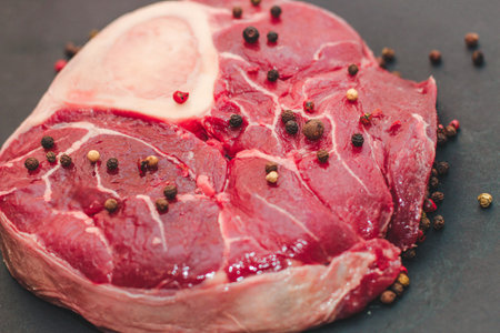 Fresh piece of meat large beef steak on the bone ossobuco with pepper on a black background.の写真素材